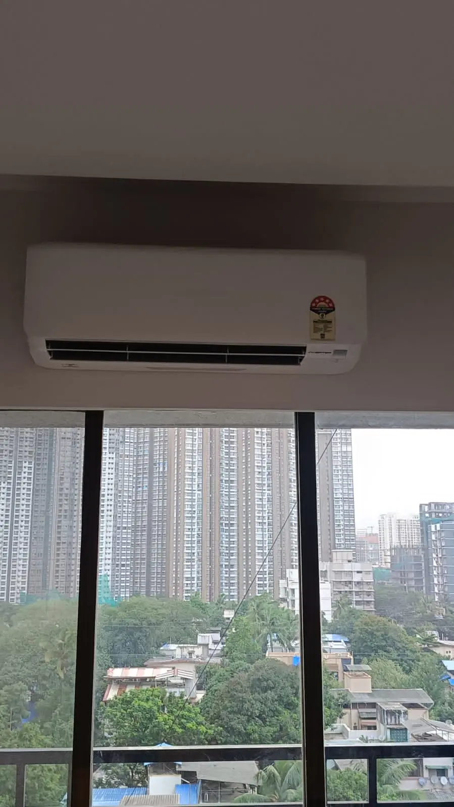 Split AC unit installed with a high-rise Mumbai skyline view, representative of the TCS Logistics VRV office fit-out