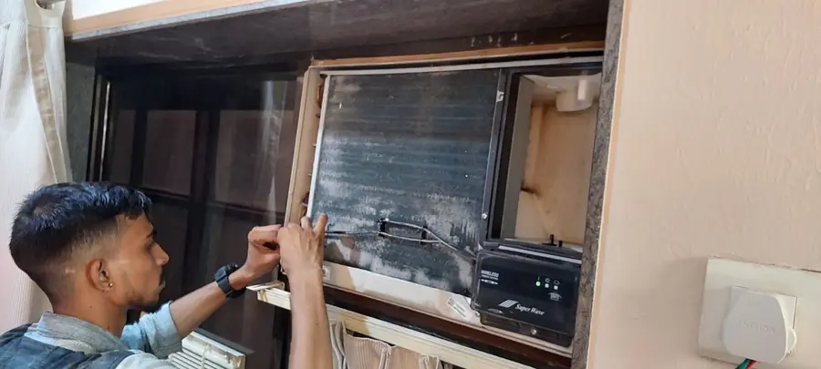 Technician repairing and cleaning a window air conditioning unit coil