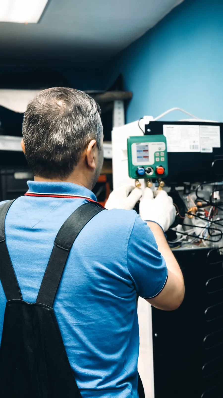Technician connecting refrigerant gauges during an air conditioning installation